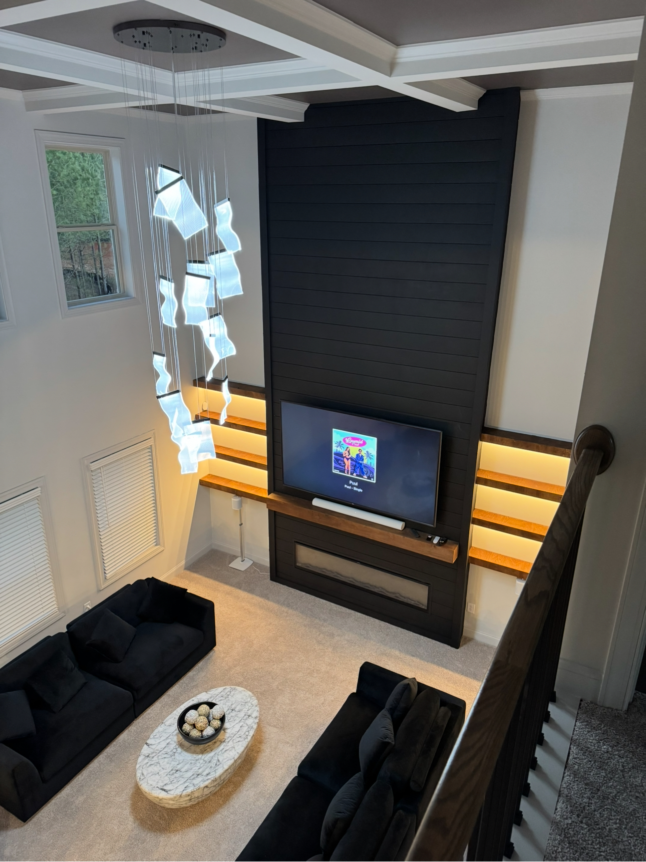 Double-height black media wall with tiered wood shelving