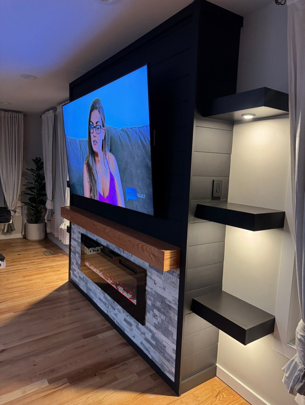 Dark shiplap accent wall with fireplace and floating black shelves